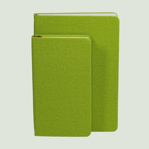 May include: Two rectangular notebooks with a textured lime green fabric cover. The larger notebook is positioned behind the smaller one, both featuring rounded corners and a clean, solid-coloured exterior design with visible white page edges.