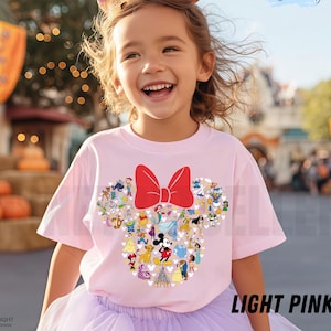 May include: A light pink t-shirt featuring a Minnie Mouse design with a red bow and various Disney characters. The shirt is worn by a smiling child. The text "LIGHT PINK" is visible at the bottom right.