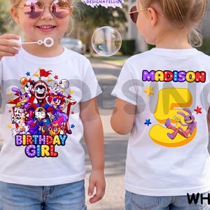 May include: A white t-shirt featuring a colorful graphic of cartoon characters under a circus tent with the text Birthday Girl on the front and the name Madison above a large yellow number five with a purple rabbit character on the back.