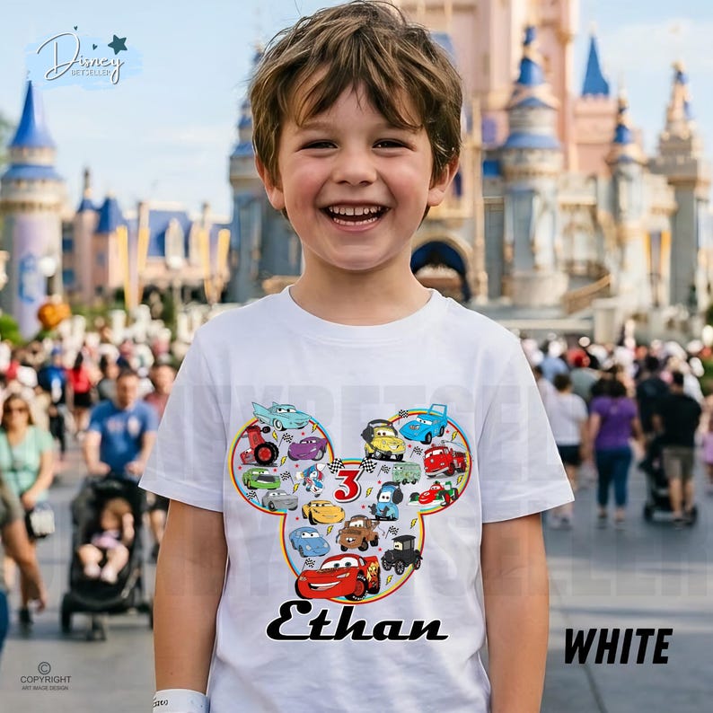 May include: A white t-shirt with a colourful graphic of cartoon cars in a Mickey Mouse head shape. The shirt has the name "Ethan" and the number "3". The word "WHITE" is printed on the bottom right.