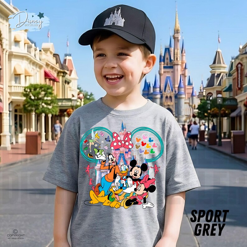 May include: A child wearing a grey t-shirt with Disney characters Mickey Mouse, Minnie Mouse, Donald Duck, Goofy, and Pluto. The shirt has a castle design and the text "SPORT GREY". They are also wearing a black baseball cap with a castle logo.