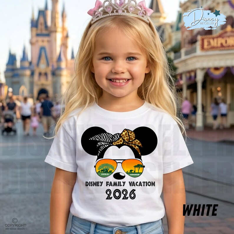 May include: A white t-shirt featuring a Minnie Mouse design with sunglasses and a headband. The shirt has the text "DISNEY FAMILY VACATION 2026" and "WHITE". A young girl is wearing the shirt and a pink tiara in front of a Disney park.