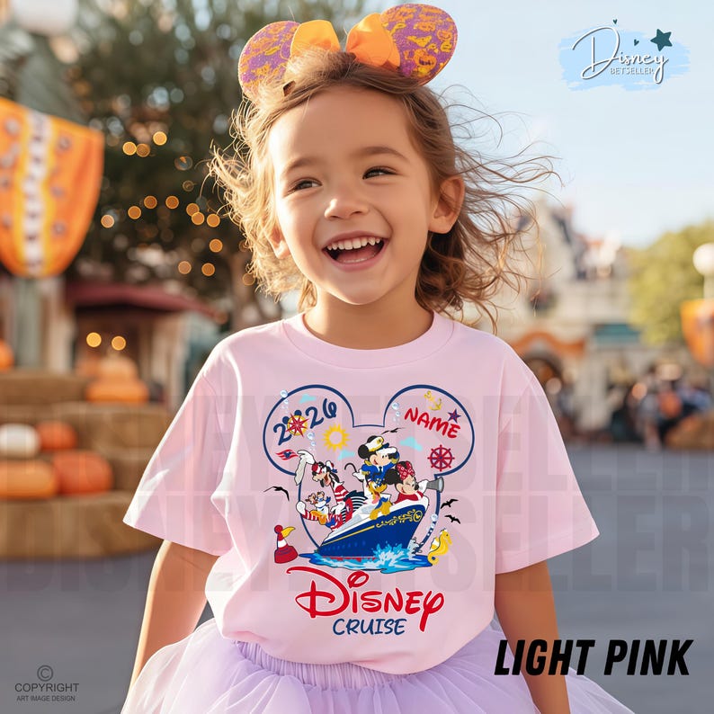 May include: A light pink t-shirt featuring a graphic of Mickey Mouse, Minnie Mouse, and Goofy on a cruise ship inside a Mickey-shaped outline. The design includes the text 2026, NAME, and Disney Cruise. The shirt is paired with a matching headband.