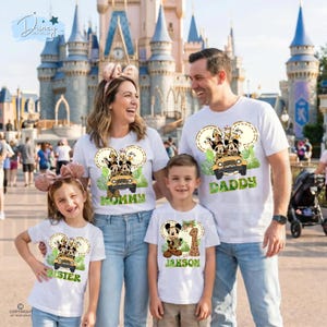May include: White t-shirts with Disney character designs. The shirts feature Mickey Mouse, Donald Duck, and other characters in a jeep. The shirts have the words "Mommy", "Daddy", "Sister", and a name printed on them. The family is smiling in front of a castle.