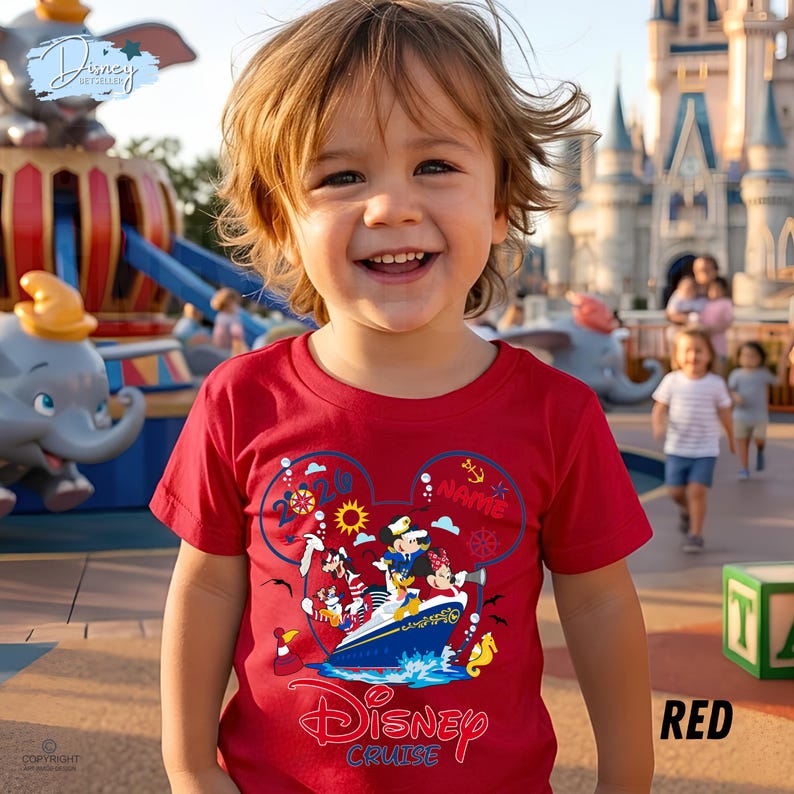 May include: A bright red short-sleeved t-shirt featuring a graphic of Disney characters on a cruise ship inside a Mickey Mouse head outline. The design includes the text "Disney Cruise" and "2026" with nautical icons like anchors and suns.