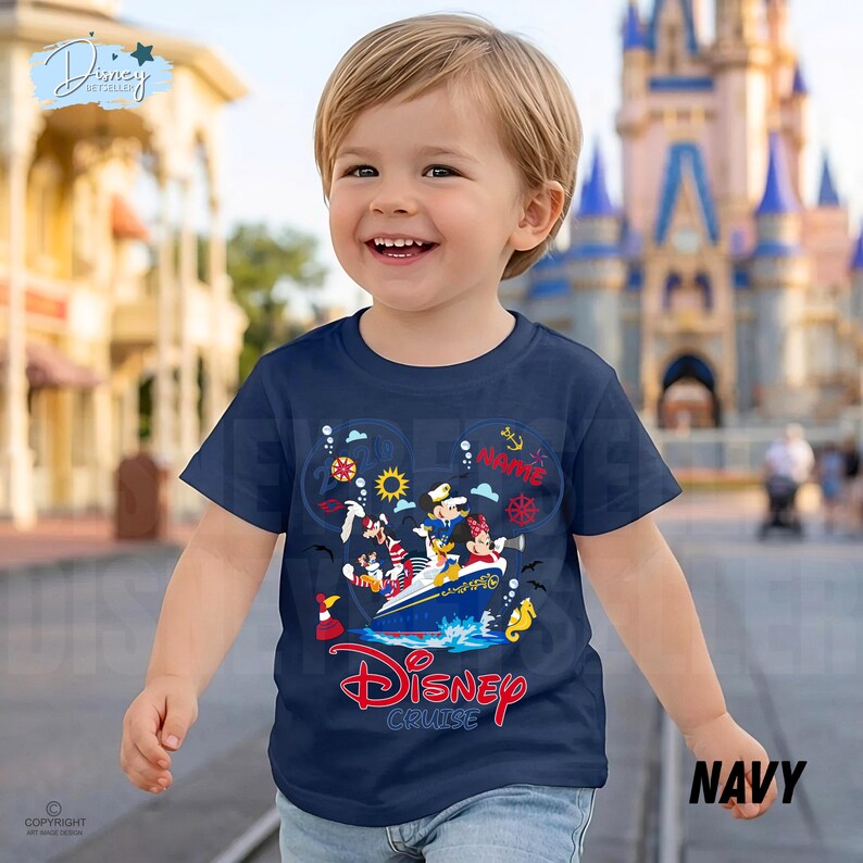 May include: A navy blue short-sleeve t-shirt featuring a graphic print of Disney characters on a cruise ship. The design includes Mickey Mouse, Minnie Mouse, and Goofy, with the text Disney Cruise in red and the word Name in red script.