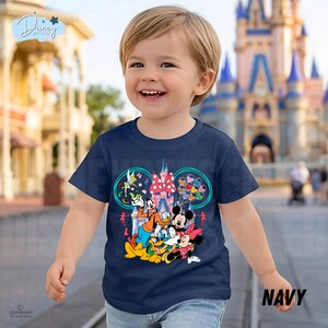 May include: Navy blue t-shirt with a Disney character graphic, including Mickey and Minnie Mouse, Donald Duck, and Goofy. The design features a castle and balloons. The word "NAVY" is printed on the bottom right.