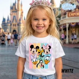 May include: A young girl wearing a white t-shirt featuring a colorful graphic of Disney characters, including Mickey Mouse, Minnie Mouse, Donald Duck, and Goofy. The shirt has vertical pastel stripes. The girl is also wearing a pink tiara.