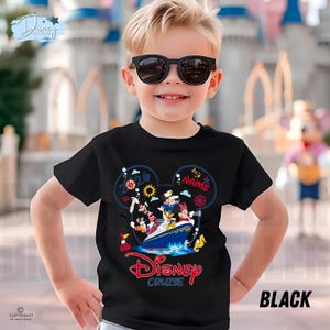 May include: A black t-shirt featuring a graphic of Disney characters on a cruise ship inside a Mickey Mouse ear silhouette. The design includes the text 2026, NAME, and Disney Cruise in red and white. The shirt has short sleeves and a crew neckline.