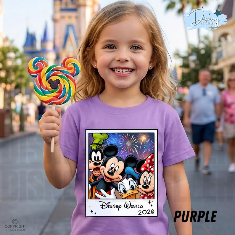 Puede incluir: Una persona joven sonr&iacute;e mientras sostiene una piruleta colorida con forma de Mickey Mouse. Lleva una camiseta morada con un gr&aacute;fico de Disney World 2026 con Mickey, Minnie, Donald y Goofy. La palabra "PURPLE" est&aacute; impresa en la camiseta.
