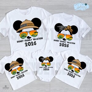 May include: White t-shirts with a Mickey Mouse design, featuring safari hats, sunglasses, and the text "DISNEY FAMILY VACATION 2026". The shirts are in various sizes, including a baby onesie, perfect for a family vacation.