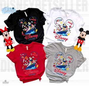 May include: Four short-sleeved t-shirts in black, white, red, and grey, each featuring a graphic of Disney characters on a cruise ship inside a Mickey Mouse ear outline. The design includes the text 2026, Name, and Disney Cruise. Two plush dolls.