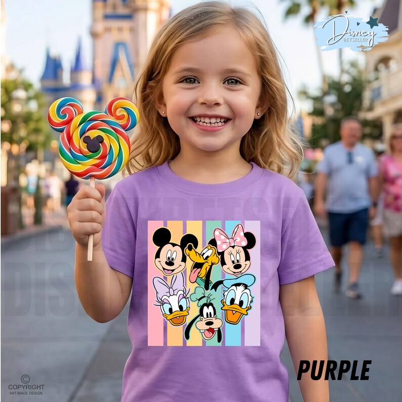 May include: A purple t-shirt featuring a colorful graphic of Disney characters, including Mickey Mouse, Minnie Mouse, Donald Duck, and Goofy. The shirt has vertical pastel stripes and the word "PURPLE" in the bottom right corner. A child is holding a colorful Mickey Mouse lollipop.