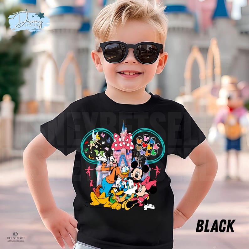 May include: Black t-shirt with a vibrant Disney character design, showcasing Mickey and Minnie Mouse, Goofy, and Donald Duck, set against a castle backdrop. The word "BLACK" is printed on the lower right.