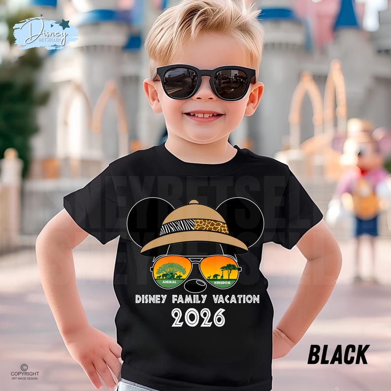May include: Black t-shirt featuring a Mickey Mouse design with safari-themed sunglasses and a hat. The sunglasses reflect a landscape with trees and animals. The text "DISNEY FAMILY VACATION 2026" is printed below the design. The word "BLACK" is printed on the bottom right.