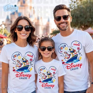 May include: Three white t-shirts featuring a graphic of Mickey Mouse and friends on a cruise ship inside a Mickey-shaped outline. The design includes the text 2026, NAME, and Disney Cruise in red and blue colours. The shirts have a crew neck design.