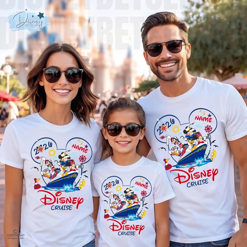 May include: Three white t-shirts featuring a graphic of Mickey Mouse and friends on a cruise ship inside a Mickey-shaped outline. The design includes the text 2026, NAME, and Disney Cruise in red and blue colours. The shirts have a crew neck design.