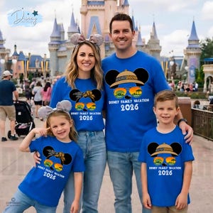 May include: A family of four wearing matching blue t-shirts with a Mickey Mouse design. The design includes sunglasses, a safari hat, and the text "DISNEY FAMILY VACATION 2026". The family is posing in front of a castle.