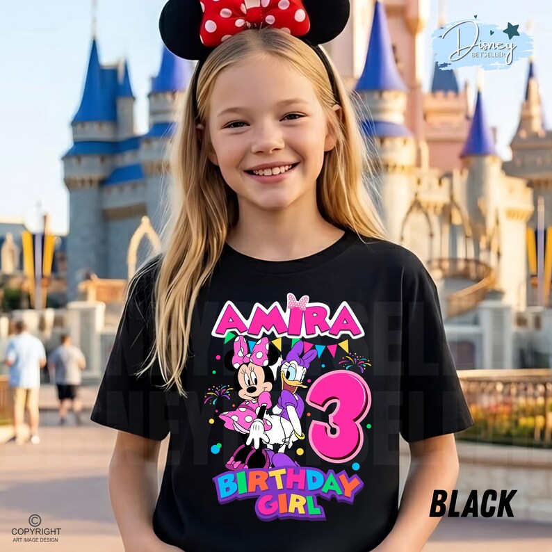 May include: A black t-shirt featuring a graphic print of Minnie Mouse and Daisy Duck with the name Amira, the number 3, and the text Birthday Girl. The design includes colorful bunting, fireworks, and confetti accents on the front of the shirt.