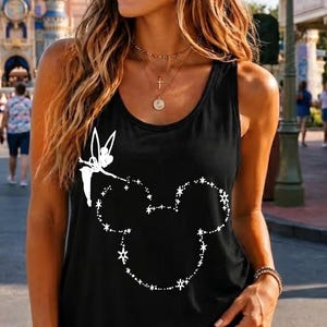 May include: A black sleeveless tank top featuring a white graphic print of a fairy silhouette and a dotted outline of a mouse ear shape. The design is composed of small star-like dots, creating a whimsical outline on the front of the garment.