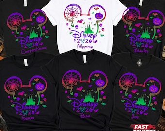May include: A collection of black and white t-shirts featuring a colorful Mickey Mouse ear silhouette graphic. The design includes a spider web, a jack-o'-lantern, bats, skulls, a castle, and the text Disney 2026 with various custom names.