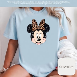 Leopard print Minnie Mouse head with sparkling galaxy-style black ears and a cheetah print bow, Disney-inspired graphic design on a transparent background. Cute Disney vacation shirt design for women, girls, and matching family trip tees