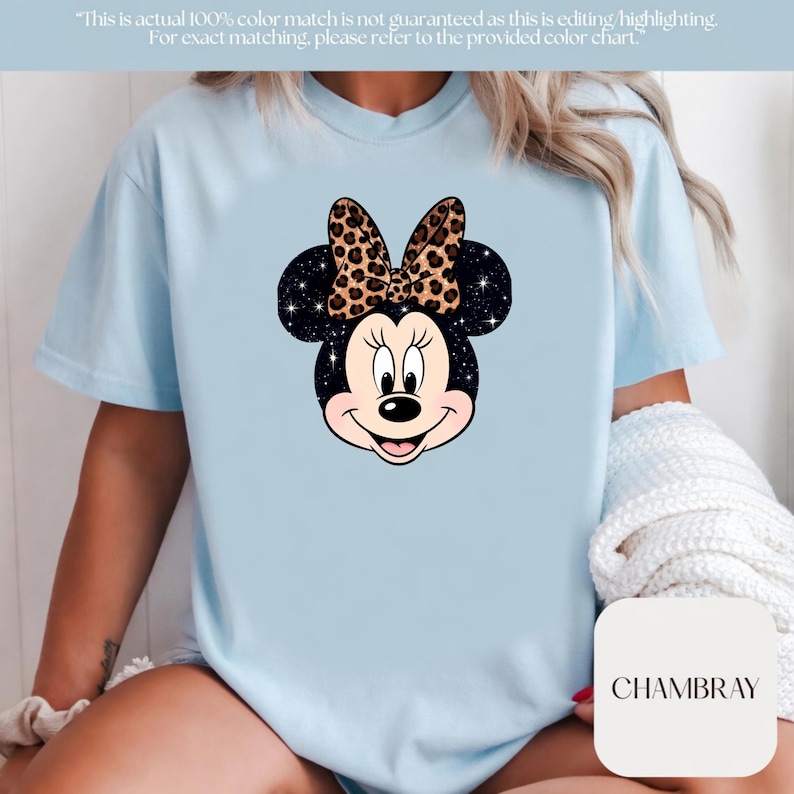 Leopard print Minnie Mouse head with sparkling galaxy-style black ears and a cheetah print bow, Disney-inspired graphic design on a transparent background. Cute Disney vacation shirt design for women, girls, and matching family trip tees