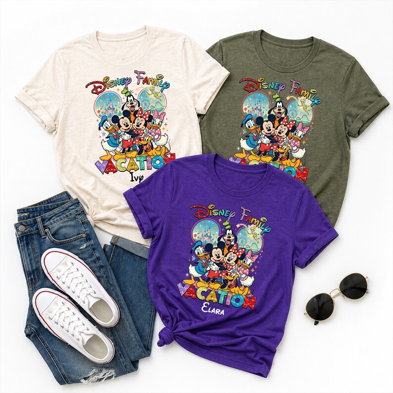 May include: Three t-shirts with a Disney Family Vacation graphic. The shirts are cream, olive green, and purple. The graphic features Mickey Mouse, Minnie Mouse, Donald Duck, and other Disney characters. The purple shirt has the name "Elara" on it. A pair of blue jeans, white sneakers, and sunglasses are also in the image.
