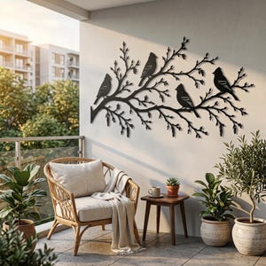 Peut inclure: Une décoration murale en métal noir représentant la silhouette de quatre oiseaux perchés sur une branche d'arbre détaillée avec de nombreuses brindilles et feuilles. L'objet est fixé sur un mur clair au-dessus d'un fauteuil et d'une table.
