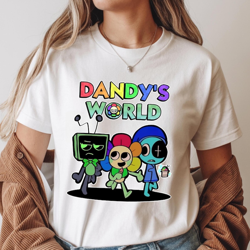 May include: White t-shirt with the text "DANDY'S WORLD" in rainbow-coloured letters. The design includes three cartoon characters: a green TV-headed figure, a flower-headed figure, and a blue-skinned figure.