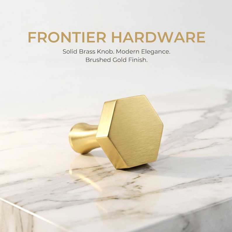 May include: A hexagonal solid brass knob with a brushed gold finish. The text FRONTIER HARDWARE, Solid Brass Knob. Modern Elegance. Brushed Gold Finish. is displayed above the knob, which features a flat front and a tapered base.