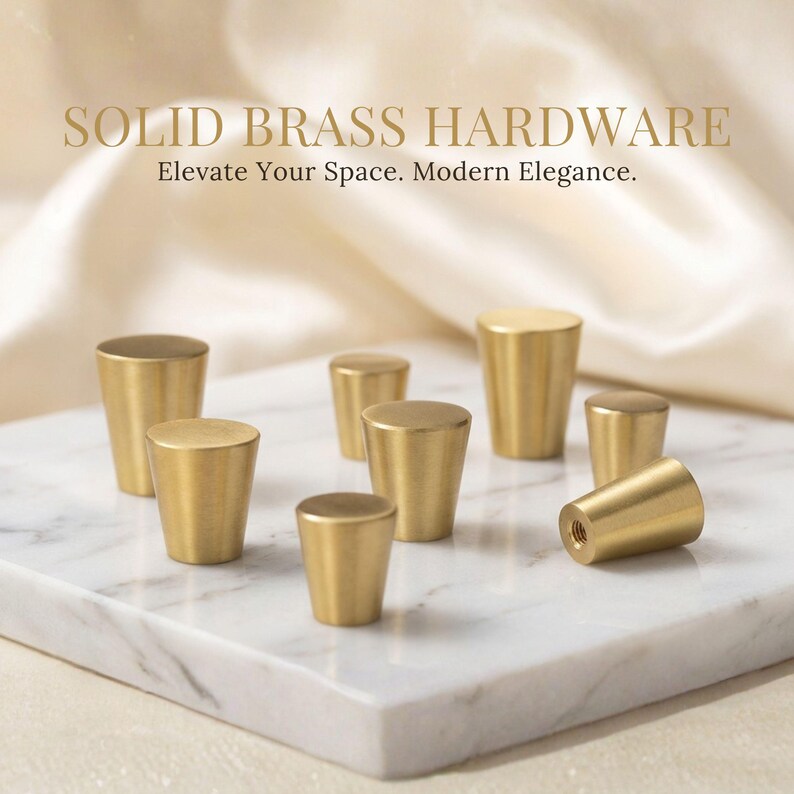 May include: A collection of solid brass cabinet knobs with a tapered, cylindrical shape and a smooth, brushed gold finish. The text SOLID BRASS HARDWARE Elevate Your Space. Modern Elegance. is displayed above the hardware items.