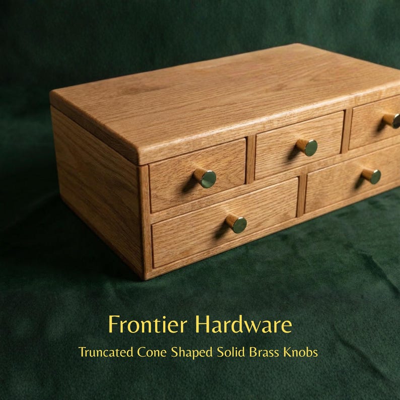 May include: A rectangular wooden storage chest featuring five drawers of varying sizes, each fitted with a small, truncated cone-shaped solid brass knob. The text Frontier Hardware Truncated Cone Shaped Solid Brass Knobs is visible below.