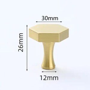 May include: A gold-colored hexagonal cabinet knob with a smooth finish. The knob features a flat top measuring 30mm in width, a base width of 12mm, and a total height of 26mm as indicated by the black dimension lines and arrows in the image.