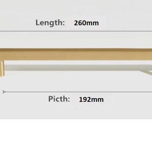Pode incluir: Um puxador de m&oacute;vel em metal dourado com design de barra linear e dois suportes cil&iacute;ndricos. O texto indica um comprimento total de 260mm e uma dist&acirc;ncia entre furos de 192mm, fornecendo especifica&ccedil;&otilde;es t&eacute;cnicas claras para a instala&ccedil;&atilde;o.