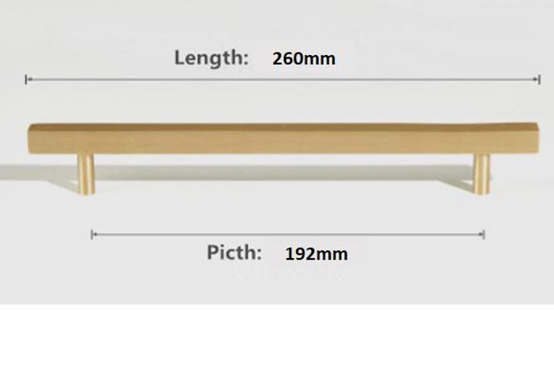 Pode incluir: Um puxador de m&oacute;vel em metal dourado com design de barra linear e dois suportes cil&iacute;ndricos. O texto indica um comprimento total de 260mm e uma dist&acirc;ncia entre furos de 192mm, fornecendo especifica&ccedil;&otilde;es t&eacute;cnicas claras para a instala&ccedil;&atilde;o.