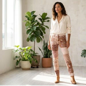 May include: A long-sleeve cream button-down shirt paired with slim-fit pants featuring a multi-tonal brown and beige patchwork paisley pattern. The pants have a mid-rise waist and a straight-leg cut, complemented by tan leather ankle boots.