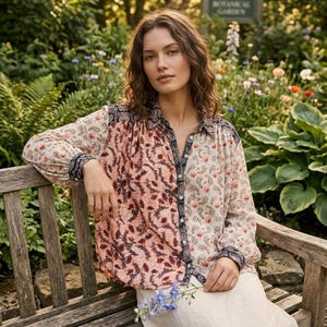 May include: A long-sleeved button-down shirt featuring a split-panel design with a peach-colored floral print on one side and a cream-colored paisley pattern on the other, accented by a dark blue and white patterned collar and button placket.