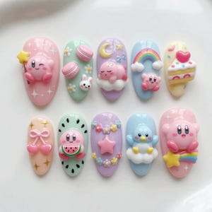 May include: A set of ten artificial nails, each with a unique design. The nails feature pastel colors and 3D embellishments, including cartoon characters, desserts, and floral accents. The designs include a rainbow, a cake, and a watermelon.