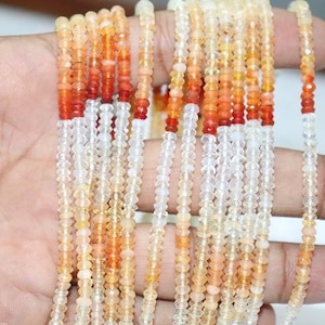May include: Multiple strands of faceted gemstone beads featuring a color gradient. The beads transition from a deep, saturated orange-red at the top to a translucent, pale yellow and clear white at the bottom, creating a distinct ombre effect.