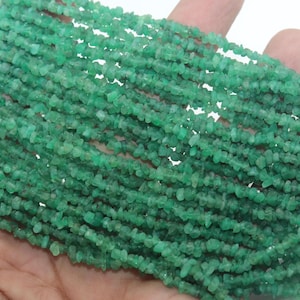 May include: Multiple strands of small, irregular, chip-shaped green gemstone beads. The beads are translucent with varying shades of emerald green, strung together in a dense, parallel arrangement to form a large, textured collection of jewelry components.