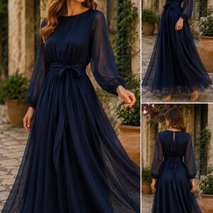 Pode incluir: Um vestido comprido azul-marinho com mangas compridas transparentes e punhos franzidos, decote redondo e cintura ajustada com um cinto de tecido a condizer. A saia &eacute; feita de tecido fluido em camadas que chega ao ch&atilde;o.