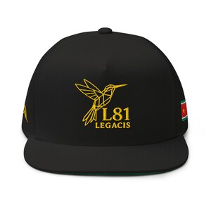 Puede incluir: Una gorra de béisbol negra con un diseño de colibrí geométrico bordado en hilo dorado en la parte frontal, acompañado por el texto L81 LEGACIS. El lateral de la gorra muestra una pequeña bandera rectangular con elementos verdes, blancos, rojos y amarillos.
