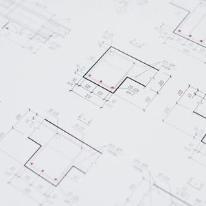 Op de afbeelding: Gedetailleerde architectonische blauwdrukken met zwarte lijnen en rode accenten op een witte achtergrond. De tekeningen bevatten verschillende geometrische vormen, afmetingen en annotaties, waarschijnlijk voor bouw- of engineeringprojecten. De afbeelding toont technische tekeningen.