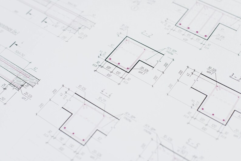 Op de afbeelding: Gedetailleerde architectonische blauwdrukken met zwarte lijnen en rode accenten op een witte achtergrond. De tekeningen bevatten verschillende geometrische vormen, afmetingen en annotaties, waarschijnlijk voor bouw- of engineeringprojecten. De afbeelding toont technische tekeningen.