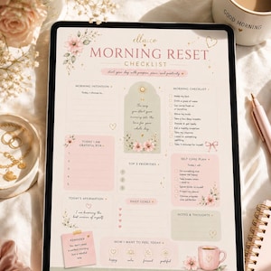 May include: A digital tablet displaying a "Morning Reset Checklist" with floral accents. The checklist includes sections for intentions, gratitude, affirmations, and self-care. A coffee mug with "Good Morning" is visible.