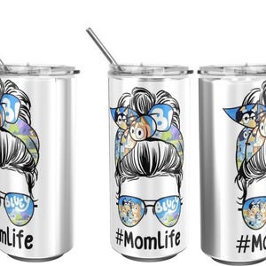 May include: A white stainless steel tumbler with a straw, featuring a cartoon design of a woman with sunglasses and a bun. The sunglasses have a Bluey design, and the text reads "#MomLife".