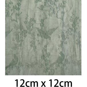 May include: A square piece of sage green fabric measuring 12cm x 12cm, featuring a repeating pattern of birds perched on flowering branches. The design is rendered in a darker shade of green against the lighter sage green background material.