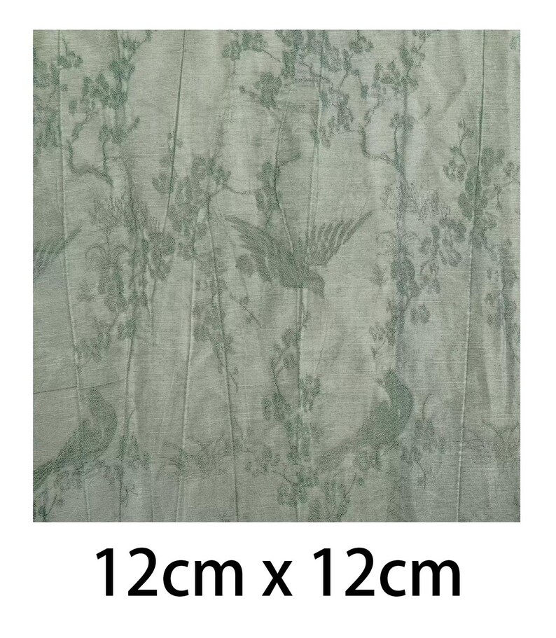 May include: A square piece of sage green fabric measuring 12cm x 12cm, featuring a repeating pattern of birds perched on flowering branches. The design is rendered in a darker shade of green against the lighter sage green background material.