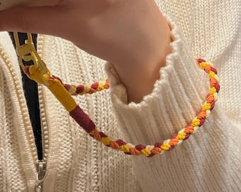 Hand-woven paracord phone straps in red and yellow, brightly colored woven rope bag accessories.